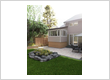 Backyard landscaping design with stone patio and garden bed