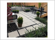 Backyard patio with interlocking pavers and landscaped garden beds